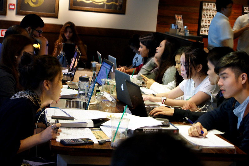 Group of generation z working in on a table with their laptops or phones